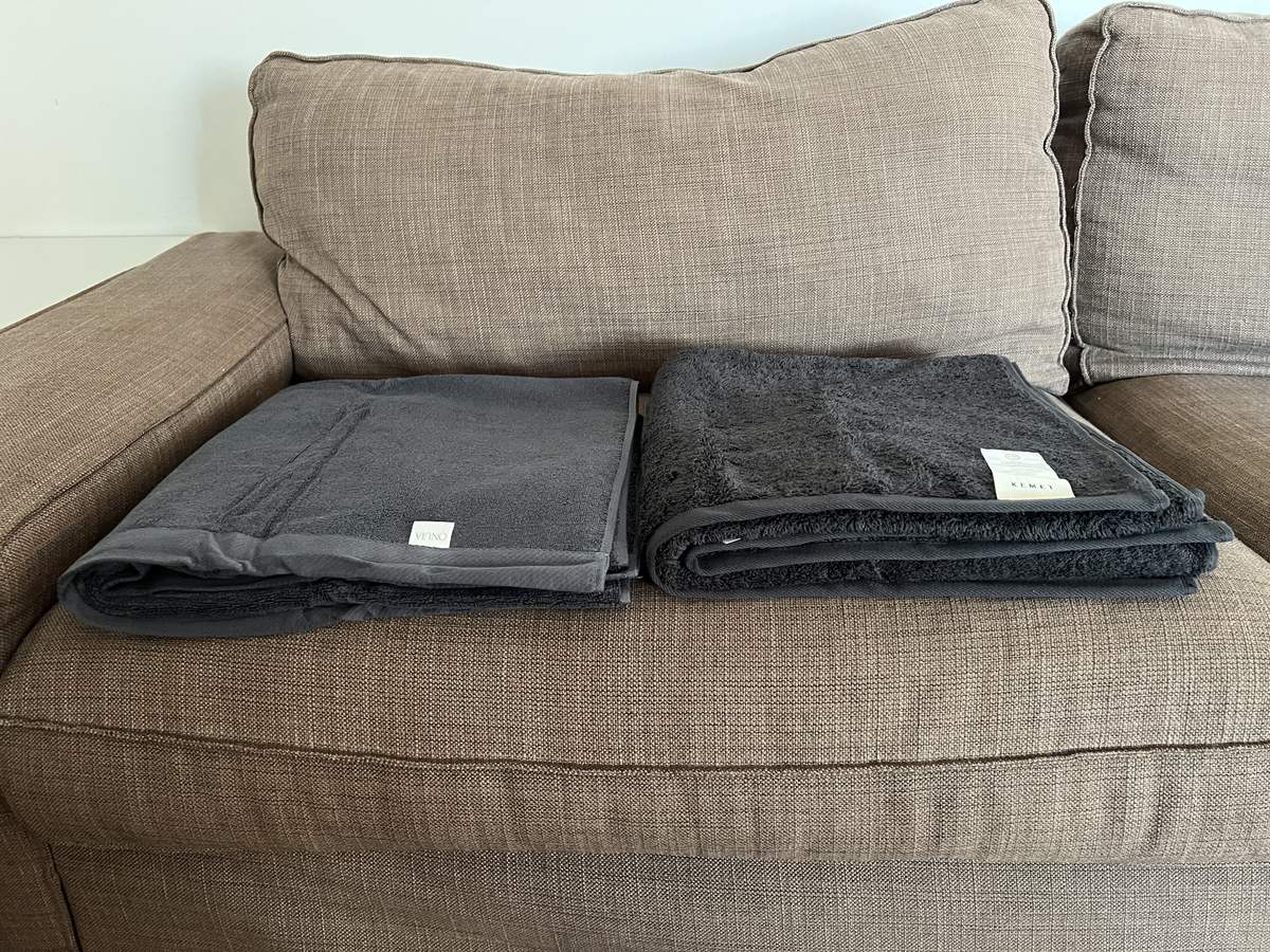 Onuia 800 GSM Heavyweight bath towel folded next to a Kemet Cotton 700 GSM Reserve bath towel, with the Kemet fold visibly taller and plusher