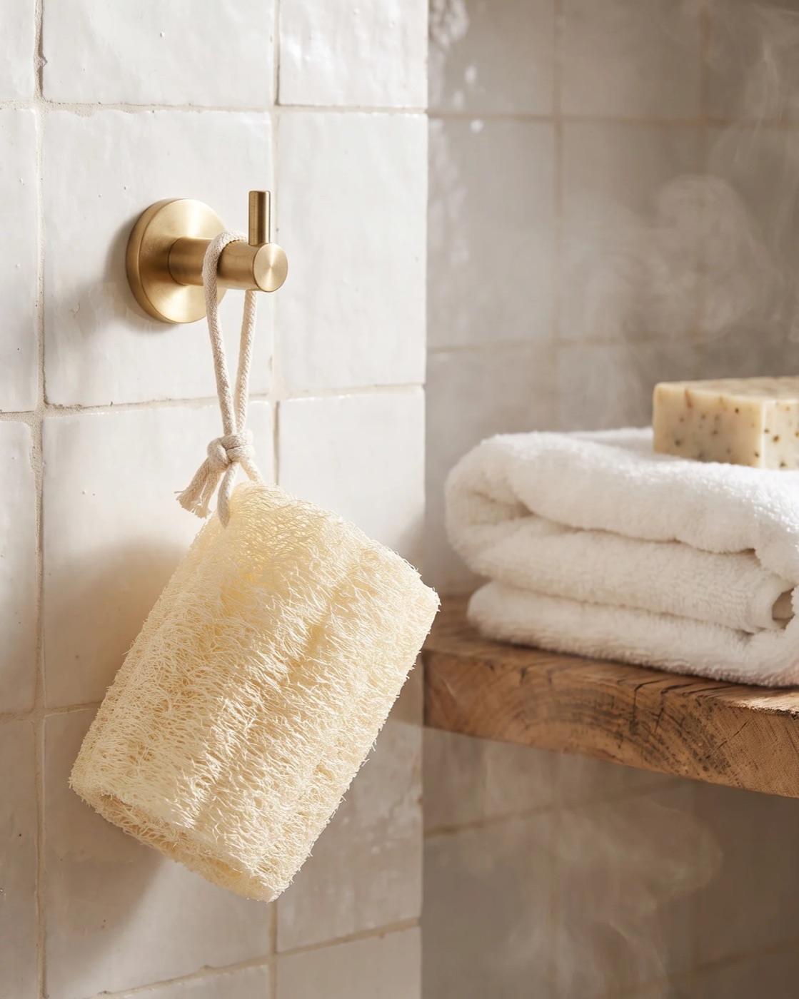 Whole natural Egyptian loofah shower sponge drying on a brass hook by its cotton rope
