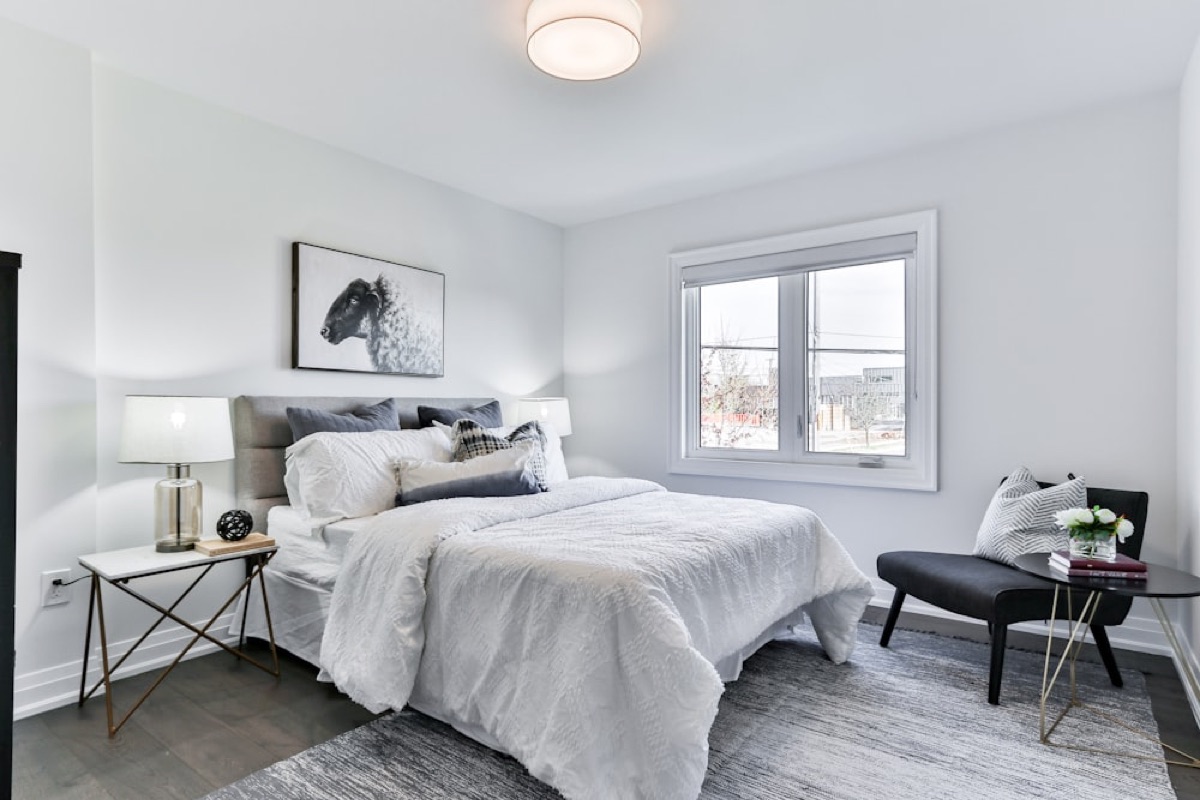 Bright bedroom with a neatly made bed dressed in crisp white cotton sheets