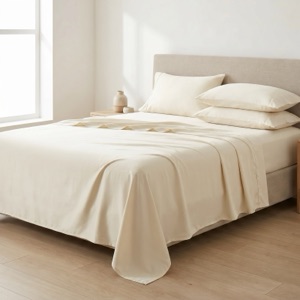 Smooth Egyptian cotton sateen sheets dressed on a bed, the polished alternative to linen's relaxed texture