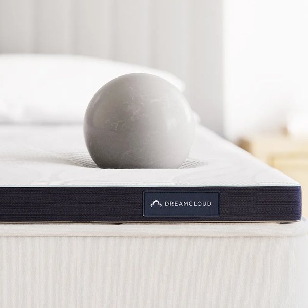 DreamCloud mattress topper corner showing the navy side band and quilted cover on a mattress