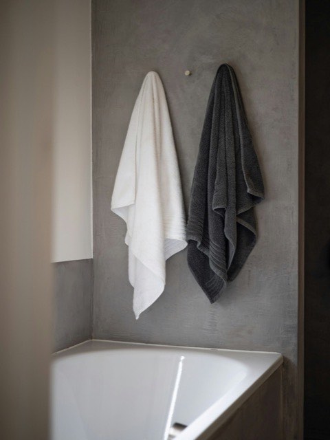 White and grey cotton towels hanging above a bathtub